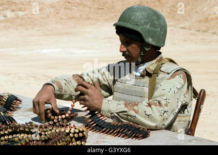 Un esercito iracheno soldato prepara le cinture di munizioni per il suo PKM 7,62-mm mitragliatrice. Foto Stock