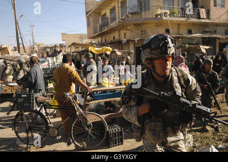 Stati Uniti Specialista dell'esercito si muove attraverso un mercato all'aperto durante una pattuglia di piede in Iraq. Foto Stock