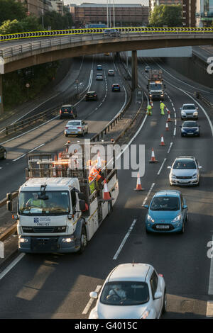 I lavoratori che mettono fuori i coni di traffico su autostrada urbana,Glasgow, Scotland, Regno Unito, Foto Stock