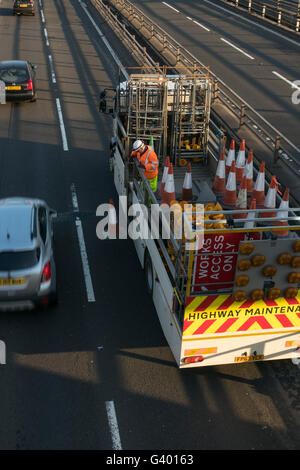 Lavoratore mettendo fuori i coni di traffico su autostrada urbana,Glasgow, Scotland, Regno Unito, Foto Stock