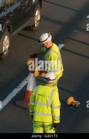 I lavoratori che mettono fuori i coni di traffico su autostrada urbana,Glasgow, Scotland, Regno Unito, Foto Stock