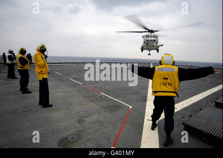 Stati Uniti Marina di Boatswain Mate dirige un H-60 elicottero sul ponte di volo della USS Tortuga. Foto Stock