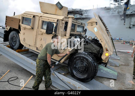 Marine utilizza una rondella a pressione per pulire il lato inferiore di un Humvee cofano. Foto Stock