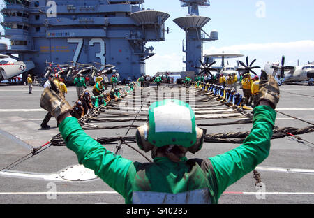 Aviation Boatswainâ€™s Mate segnali per i marinai per impostare il velivolo barricade. Foto Stock