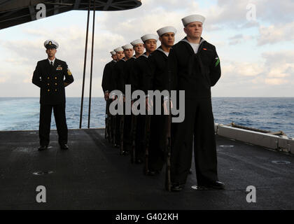 La guardia d'onore si erge a parade di riposo durante una sepoltura in mare. Foto Stock
