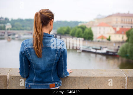 Giovane donna che guarda sul fiume godendo la vista. Foto Stock