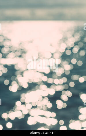 Sfocato di sfondo sfocato sole brilla sulla superficie dell'acqua, vintage immagine dai toni Foto Stock