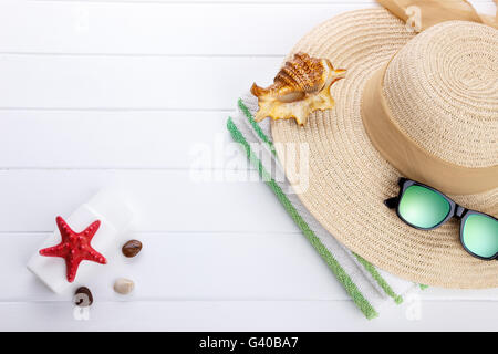 Spiaggia accessori su sfondo di legno per la stagione estiva o il concetto di vacanza. Cappello, occhiali da sole telo da spiaggia, scottature lozione. Spazio per Foto Stock