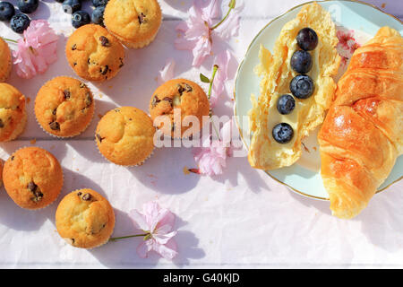 Una deliziosa colazione con croissant freschi e bacche mature sul vecchio sfondo di legno, fuoco selettivo Foto Stock