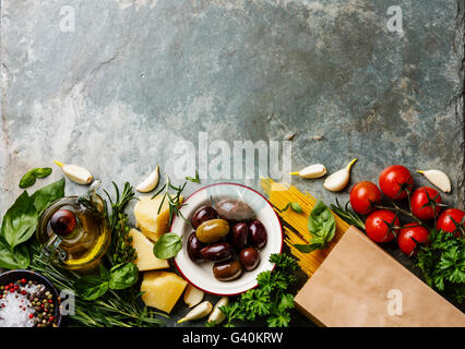 Il cibo italiano ingredienti sfondo con spaghetti, parmigiano, olive, olio e basilico Foto Stock