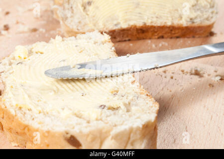 Coltello posa su un fresco imburrato fetta di miele e olio di semi di girasole di pane bianco Foto Stock