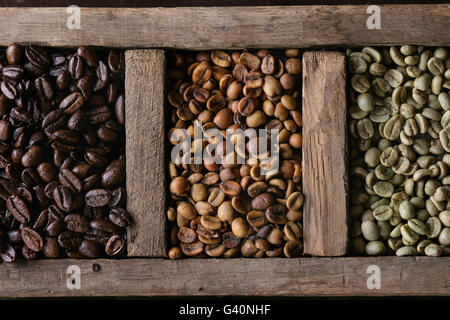 Il cibo con sfondo verde e marrone e non torrefatto Caffè decaffeinato e nero caffè torrefatto in grani nella vecchia scatola di legno. Vista dall'alto. Close up Foto Stock