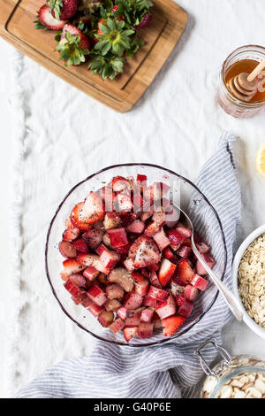 Un grande cesto di fragole a fette e rabarbaro è spruzzata con semi di papavero e fotografata dalla vista dall'alto. Foto Stock