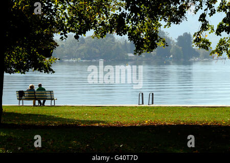 Giovane sitted sul banco di lavoro e il paesaggio del lago di Annecy e le montagne in Savoia, Francia Foto Stock