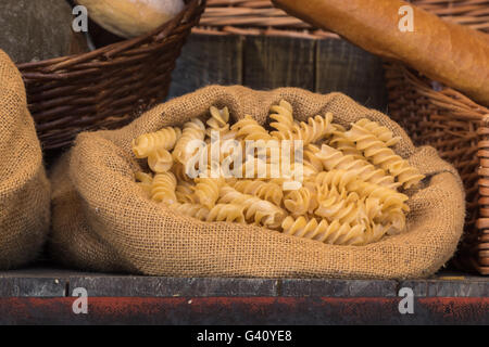 Non cotti Pasta italiana nel sacco di iuta sul tavolo di legno Foto Stock