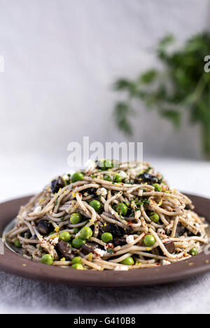 Una piastra piena di Creamy Mushroom Pasta con i piselli freschi e ricotta è fotografata dalla parte anteriore. Foto Stock