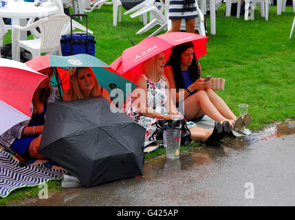 Quattro donne in abiti smart shelter sull'erba dalla pioggia. Foto Stock