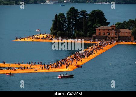 Paratico, Italia. Il 18 giugno, 2016. I visitatori a piedi attraverso pontili galleggianti rivestito in tessuto di colore arancione come parte del progetto "i pontili galleggianti' di Christo sul Lago d'Iseo Lago off di Paratico, Italia, 18 giugno 2016. Christo aveva un molo costruito da Paratico verso l' isola di Pesciera e coperto il molo e la riva in tessuto. Il progetto artistico di Christo sulla parte settentrionale del lago italiano apre il 18 giugno e continua fino al 03 luglio 2016. Foto: MICHAEL KAPPELER/dpa/Alamy Live News Foto Stock