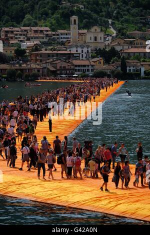 Paratico, Italia. Il 18 giugno, 2016. I visitatori a piedi attraverso pontili galleggianti rivestito in tessuto di colore arancione come parte del progetto "i pontili galleggianti' di Christo sul Lago d'Iseo Lago off di Paratico, Italia, 18 giugno 2016. Christo aveva un molo costruito da Paratico verso l' isola di Pesciera e coperto il molo e la riva in tessuto. Il progetto artistico di Christo sulla parte settentrionale del lago italiano apre il 18 giugno e continua fino al 03 luglio 2016. Foto: MICHAEL KAPPELER/dpa/Alamy Live News Foto Stock