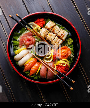 Set di sushi nigiri, rotoli e sashimi serviti in Giappone tradizionale Sushioke nero piatto rotondo Foto Stock