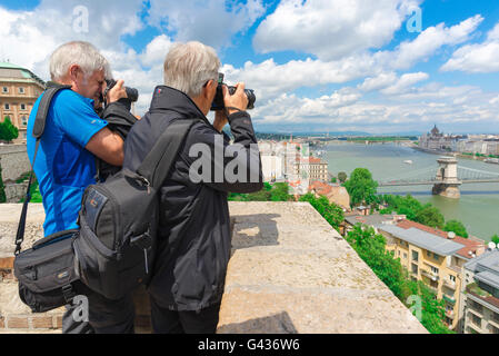 Uomini con macchine fotografiche, vista di un paio di turisti maschi che scattano foto del centro di Budapest da un punto di vista vicino al Palazzo reale della città, Ungheria. Foto Stock