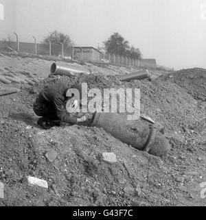 Due uomini della Royal Air Force della RAF Debden, Essex, guardano da vicino a una bomba da 1,000 libbre sradolata a Southall Lane, Heston e Isleworth, Middlesex da uomini che lavorano su scavi in connessione con l'estensione dell'autostrada M4. Foto Stock