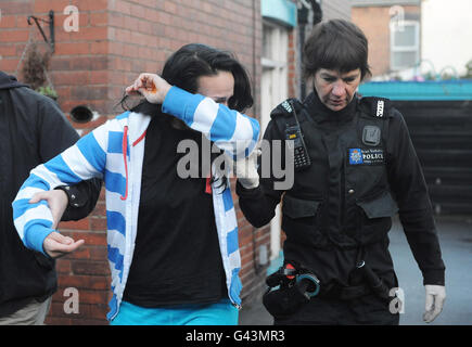 Una donna è guidata via da agenti di polizia di una casa a Rotherham, nello Yorkshire meridionale, durante un'operazione congiunta di polizia e Agenzia di frontiera. Foto Stock
