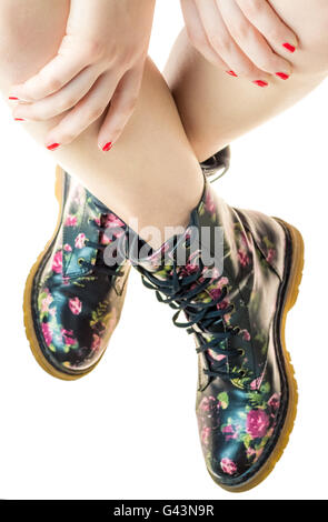 Stile militare stivali con fiori di decorazione su un mani con polis chiodi rossi Foto Stock