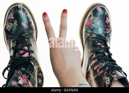 Stile militare stivali con fiori di decorazione su un mani con polis chiodi rossi Foto Stock