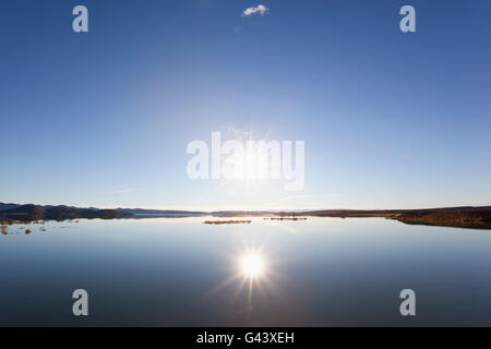 Tramonto a un lago con il cielo azzurro e acqua di riflessione. Foto Stock