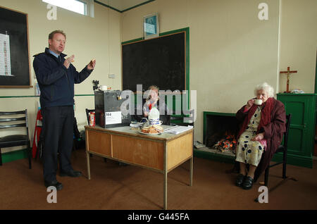 Garda Martin Reilly di Achill chiacchiera con gli isolani e gli elettori Annie Calvey e Bridgie o'Malley con il tè e i sandwich nel seggio elettorale di Schil Mhuire su Inishbigle (Inis Bigil in irlandese), una piccola isola abitata al largo della costa della contea di Mayo in Irlanda, Poiché la votazione ha inizio nelle elezioni generali irlandesi del 2011. Foto Stock