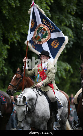 Royal Alfiere Rory J. monaci conduce i piloti che prendono parte alla Selkirk Equitazione comune, una secolare tradizione nel royal burgh di Selkirk Scottish Borders. Foto Stock