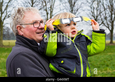 Nonno tenendo la sua nipote guardando l'eclisse solare parziale (Derbyshire, XX marzo 2015, UK) Foto Stock