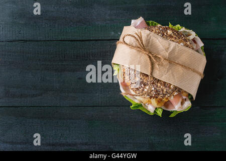 Tappezzate grano intero bagel con cipolla fritti, insalata verde e prosciutto crudo su legno scuro dello sfondo a trama. Vista superiore Foto Stock