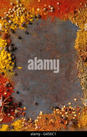 Sfondo speziato con assortimento di differenti peperoncino e pepe della Giamaica peperoni e mix di altre spezie oltre il vecchio ferro arrugginito backgro Foto Stock