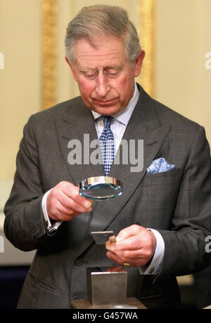 Il Principe di Galles esamina il suo lavoro dopo che ha segnato un pezzo d'argento durante una visita, con la Duchessa di Cornovaglia, a Goldsmiths Hall, Londra. Foto Stock