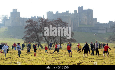 La gente apprezza la tradizionale partita di calcio del martedì Shrove al castello di Alnwick, nel Northumberland. Foto Stock