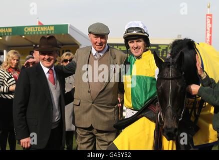 Jockey Tony McCoy (centro a destra) festeggia con l'allenatore Jonjo o'Neill (a sinistra) e il proprietario Trevor Hemmings dopo aver vinto il Ryanair Chase (registrato come Festival Trophy Chase) che corre Albertas il giorno di San Patrizio, durante il Cheltenham Festival. Foto Stock