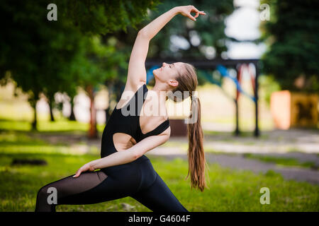Pretty Woman facendo esercizi yoga nel parco Foto Stock