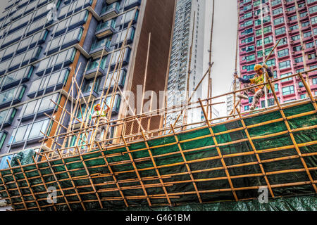 Hong Kong - Marzo 31, 2015: due lavoratori edili Costruzione di un ponteggio di bambù in un cantiere di Hong Kong. Foto Stock