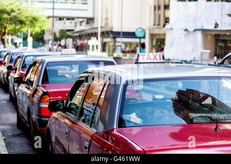 Una flotta di Hong Kong i taxi in attesa presso una stazione dei taxi. Hong Kong i taxi sono facilmente riconoscibili per i loro colori bianco e rosso,. Foto Stock