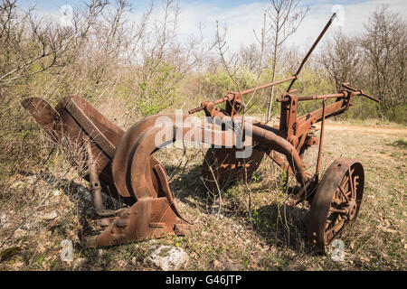 Vecchio di ferro arrugginito aratro abbandonato in un campo incolto. Foto Stock