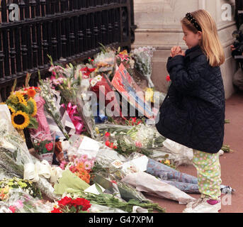 Una giovane ragazza dice una preghiera mentre lei depone un mazzo di fiori in memoria di Diana, principessa del Galles fuori Buckingham Palace. La principessa, il suo amico Dodi Fayed e il loro autista sono stati uccisi in un incidente mortale di auto a Parigi la scorsa notte. Foto Stock