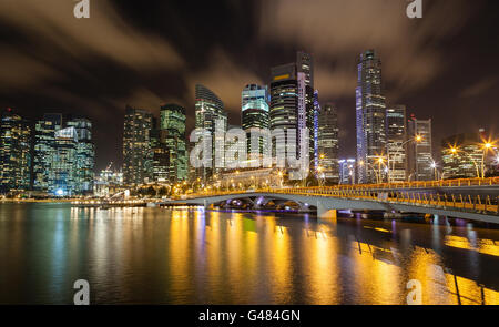 Scena notturna di Singapore cityscape che mostra la nuova costruzione Giubileo ponte che collega il Parco Merlion e alla passeggiata del lungomare in f Foto Stock