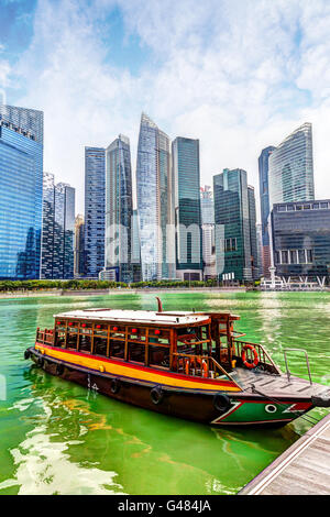 Un dock sulla bumboat presso il Marina Bay con grattacieli in Singapore business district in background. Rendering HDR. Foto Stock