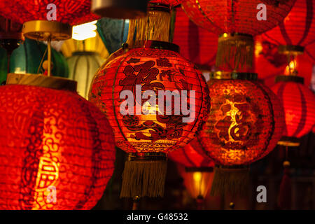 La messa a fuoco su di una lanterna cinese con le parole "Benedizioni' stampati su di esso tra una schiera di lanterne rosse in background. Foto Stock