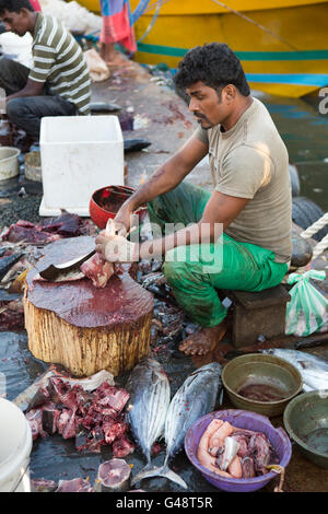 Sri Lanka, Mirissa Harbour, lavoratore tagliare il pesce in vendita in piccole quantità Foto Stock