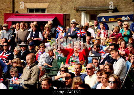 La gente onda le bandiere di Unione mentre guardano il matrimonio reale ad una festa di strada a Wells-next-the-Sea in Norfolk. Foto Stock