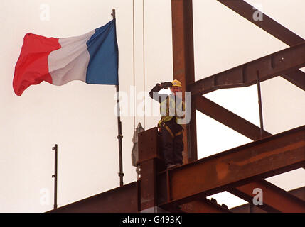 Un operaio britannico saluta con il francese Tricolor che vola accanto a lui, di fronte a una piazza del Canada, a Canary Wharf, oggi (venerdì), dove il primo ministro Tony Blair, il suo omologo francese Lionel Jospin e il presidente francese Jacques Chirac hanno partecipato a una conferenza stampa, come parte del vertice britannico-francese. Si veda il PA Story POLITICS Summit. Foto di Rebecca Naden. Foto Stock