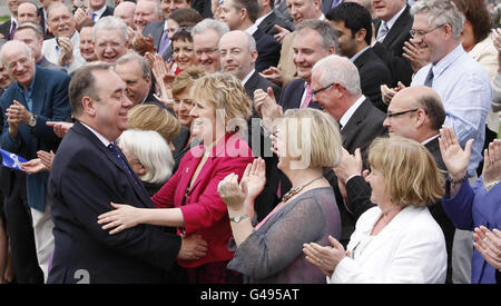 Il leader della SNP Alex Salmond viene accolto dai nuovi membri della SNP al di fuori del Parlamento scozzese di Edimburgo, dopo la vittoria senza precedenti dell'SNP alle elezioni del Parlamento scozzese. Foto Stock